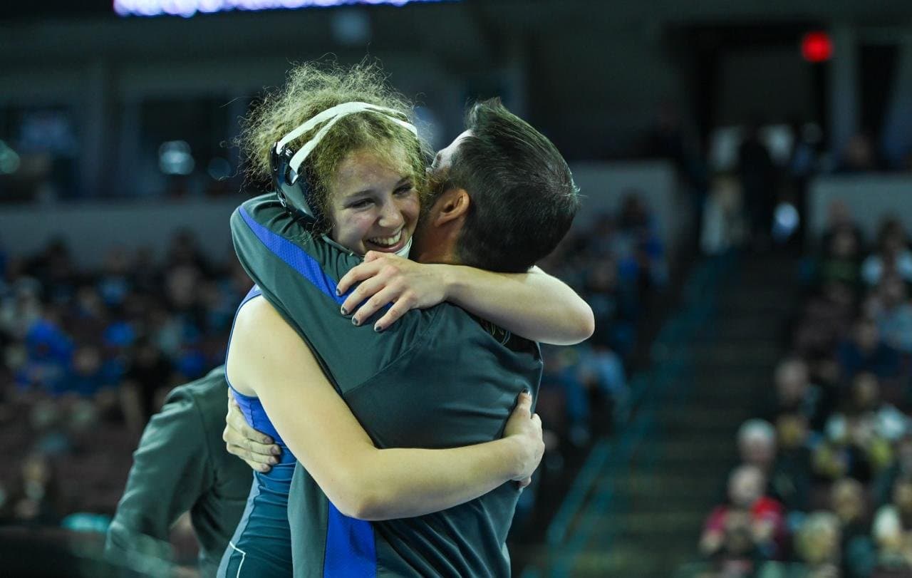 Coach hugging a Mira Mesa wrestler after a championship match